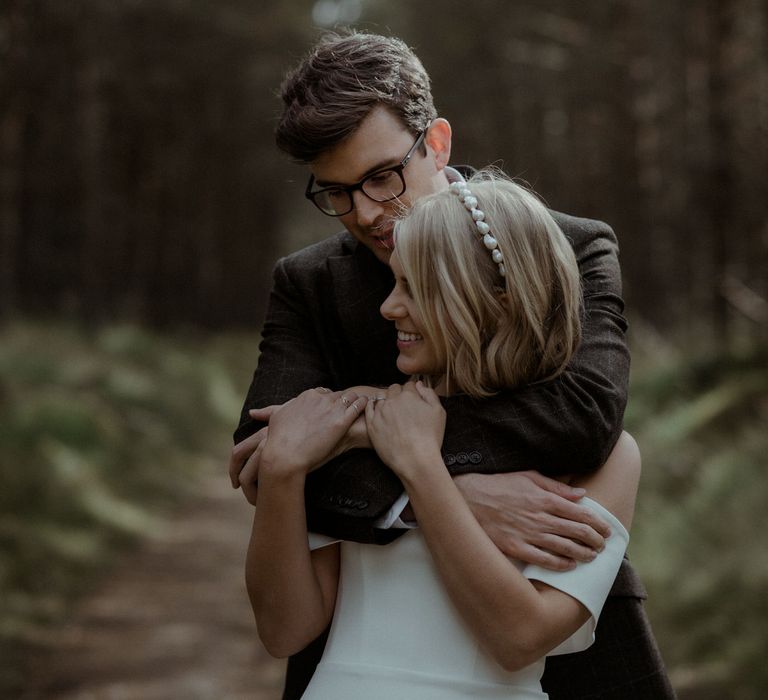 Groom embraces bride outdoors after Scottish elopement 