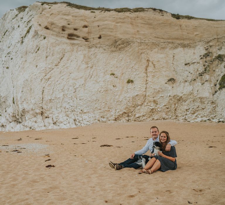 Bride and groom to be engagement shoot sat on the beach in Dorset