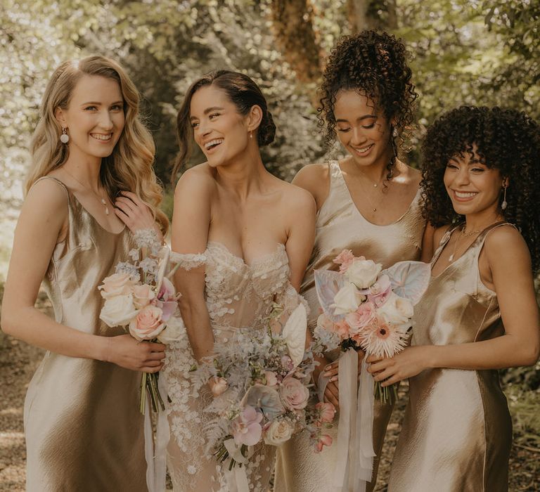 Bridal party portrait with bride in an off the shoulder dress and bridesmaids in gold satin slips 