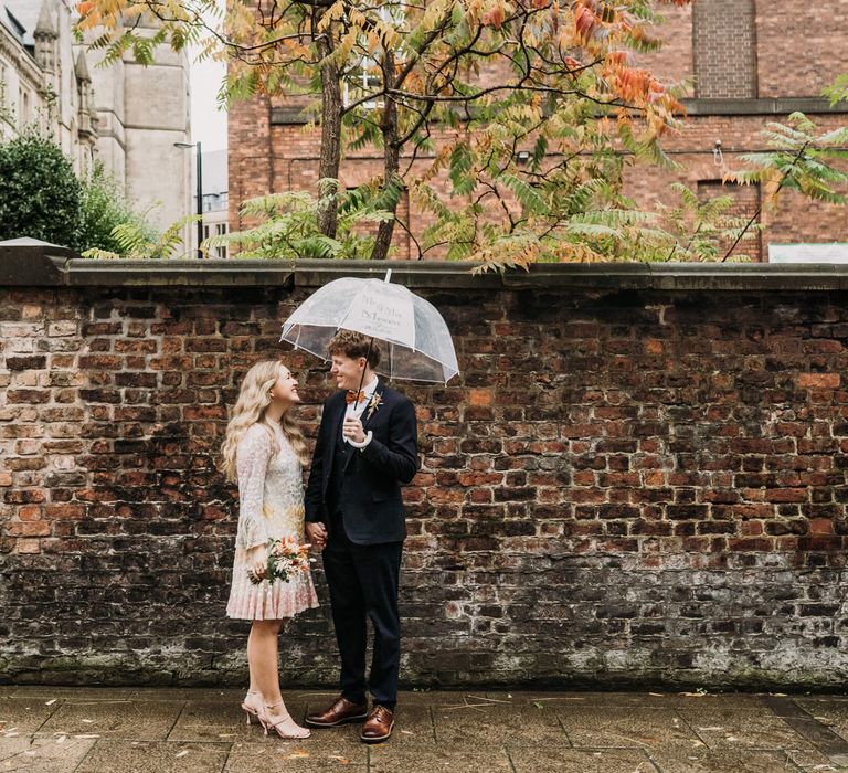 Bride and groom in the rain on their wedding day in Manchester