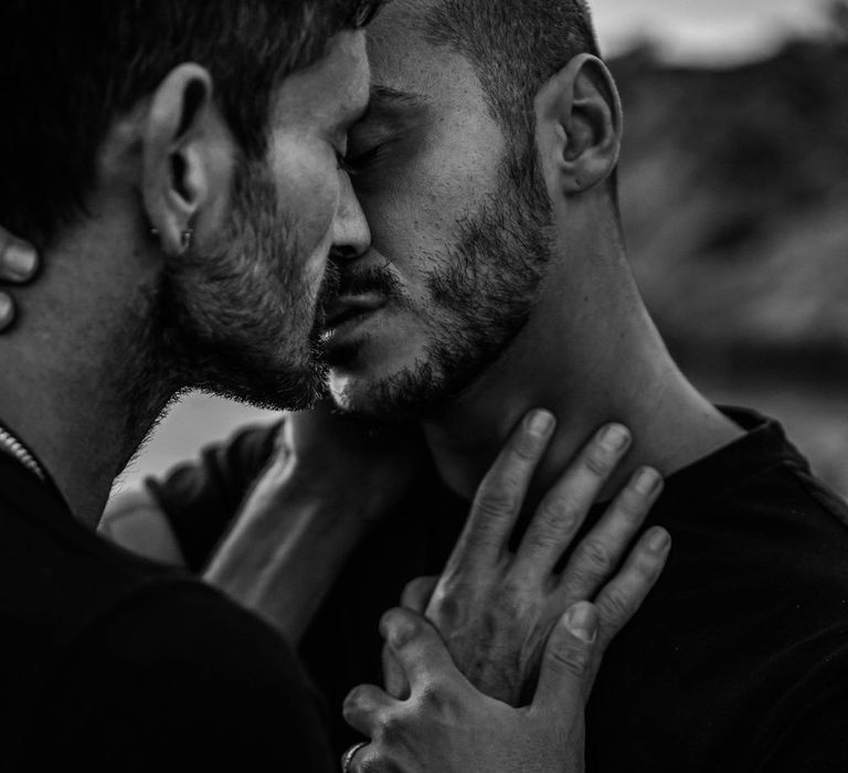 Black & white image of grooms holding one another's hands 