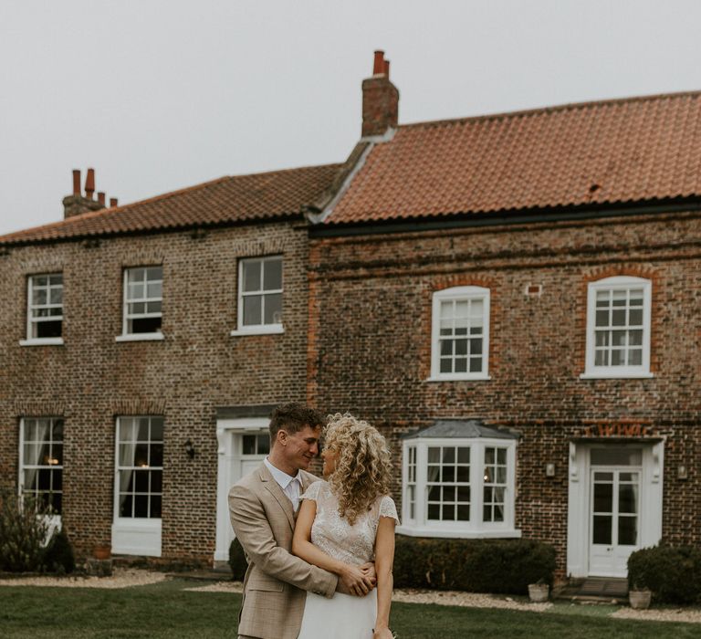 Curly haired bride and groom at Hornington Manor, the bride wearing bridal separates and carrying a bouquet of roses and wild flowers