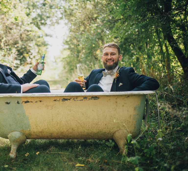 Groom & groomsmen sit in roll top bath with drinks