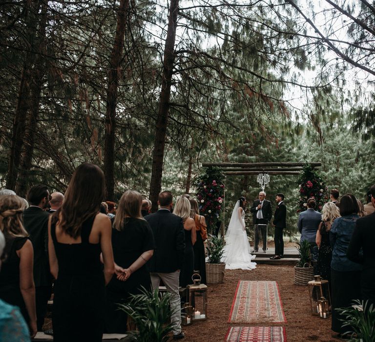 Bride and groom getting married at a moody romantic outdoor wedding with Persian rug aisle