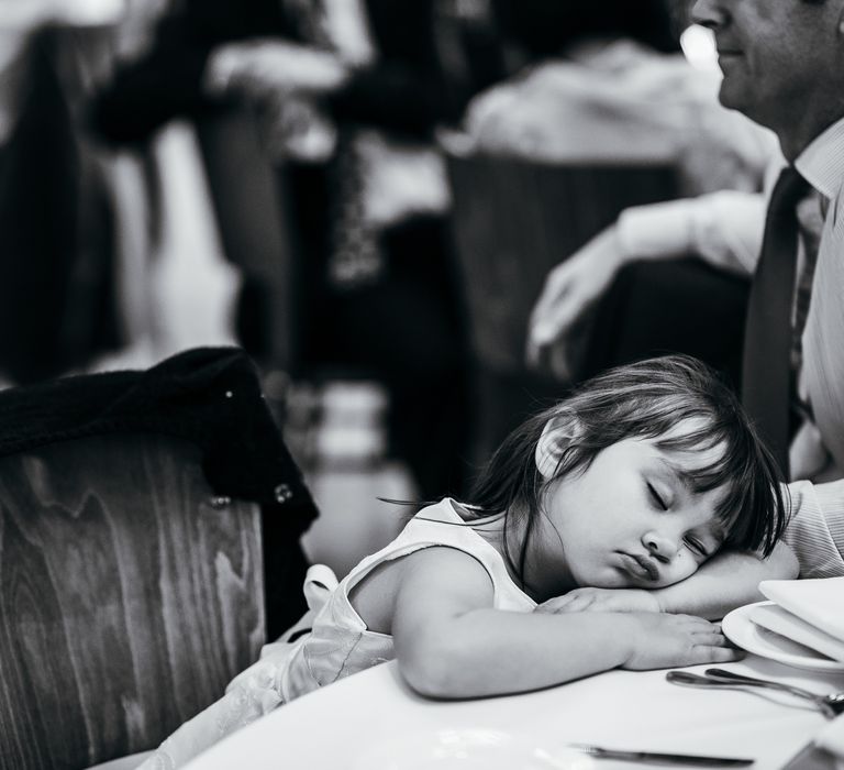 Little girl sleeps on table during wedding reception