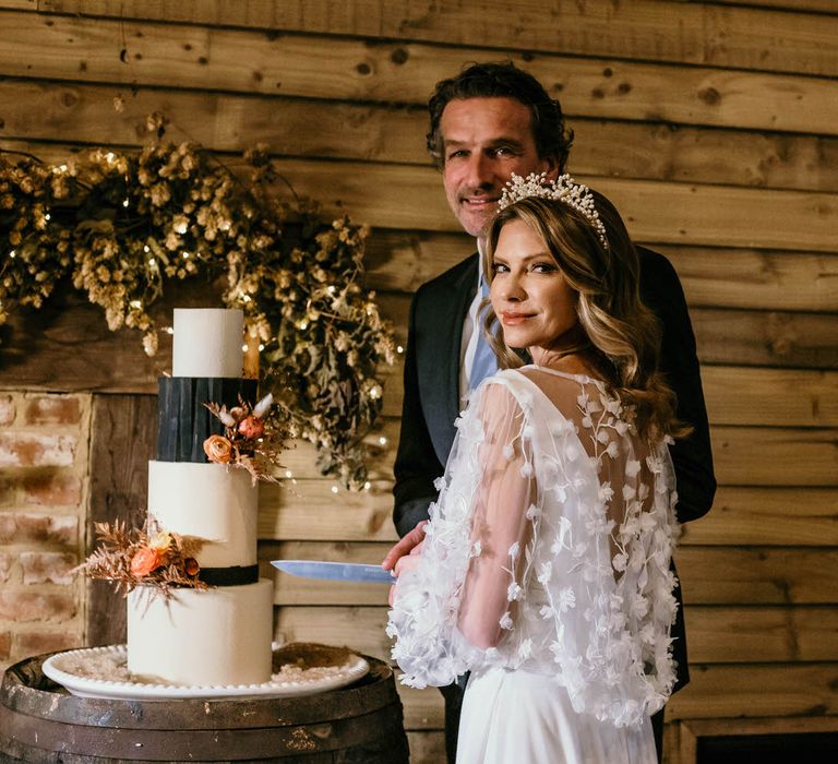 Bride and groom cutting into a four tier black and white wedding cake