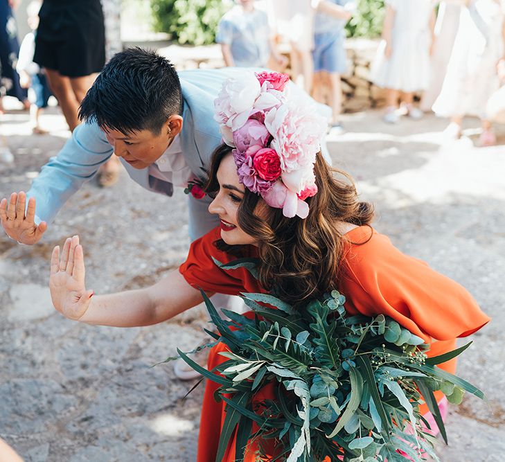 Brides bend down to high-five children on their wedding day outside in Menorca