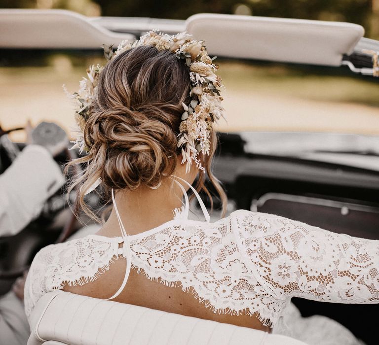 Boho bride in a lace open back wedding dress with loosely pinned bridal bun and dried flower crown 