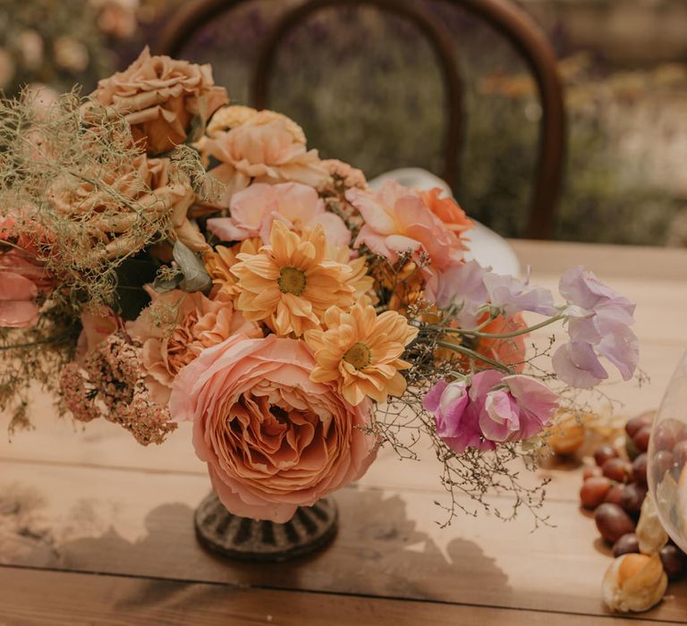 centrepiece flowers in a vessel with pastel orange, peach, coral and pink wedding flowers 