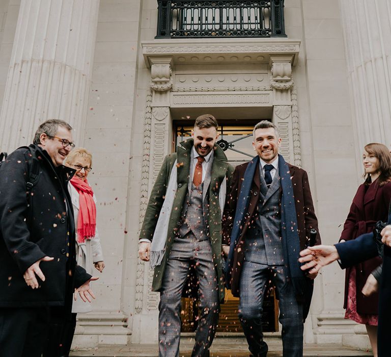 Grooms leave the Old Marylebone Town Hall as wedding guests throw confetti around them after intimate ceremony