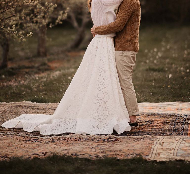 golden hour portrait with bride and groom in casual wedding attire dancing outside under a string of festoon lights 