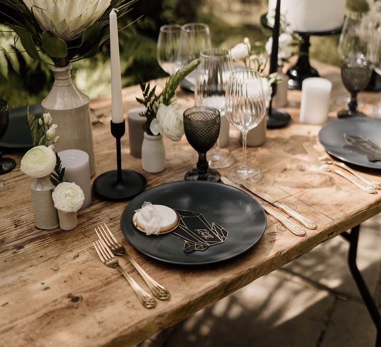 Wedding table decor with black tableware, candlestick holders, gold bets and on the day wedding stationery 