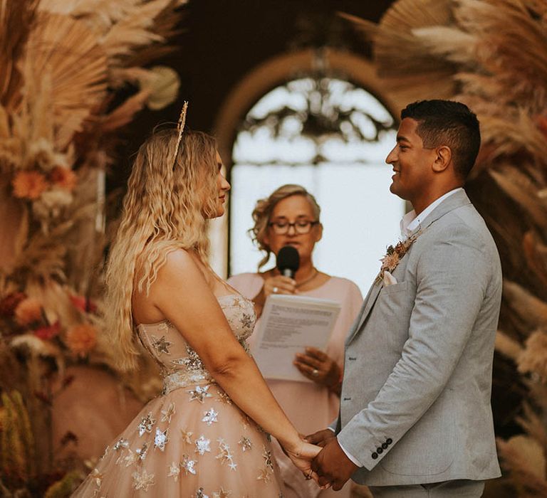 Bride & groom hold hands and look lovingly at one another on wedding day