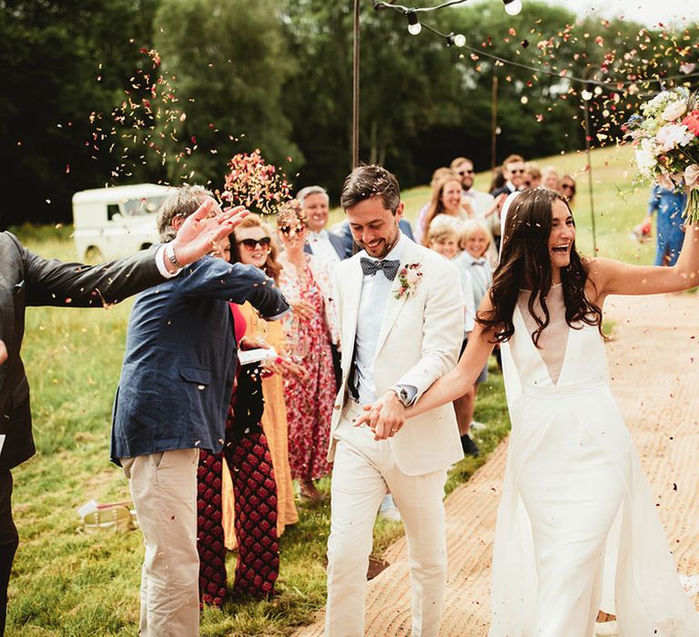 Bride & groom walk down the aisle on their wedding day whilst confetti is thrown around them