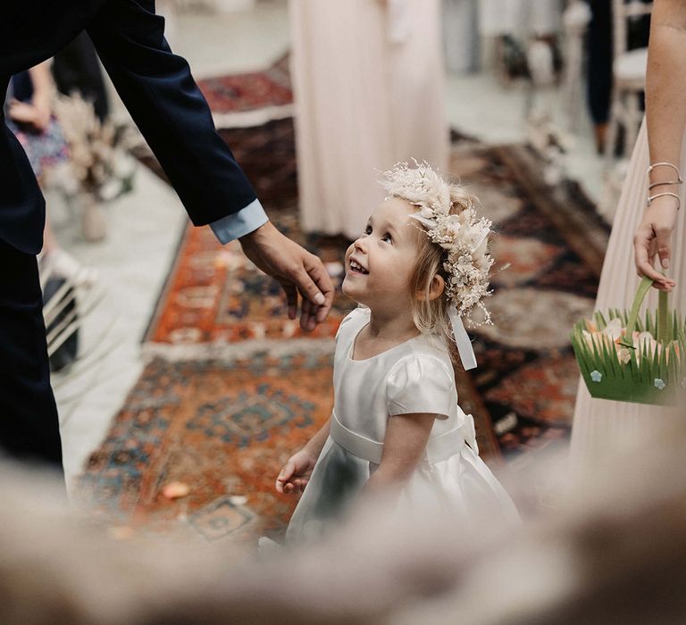 Flower girl wears white dress complete with neutral toned dried floral crown