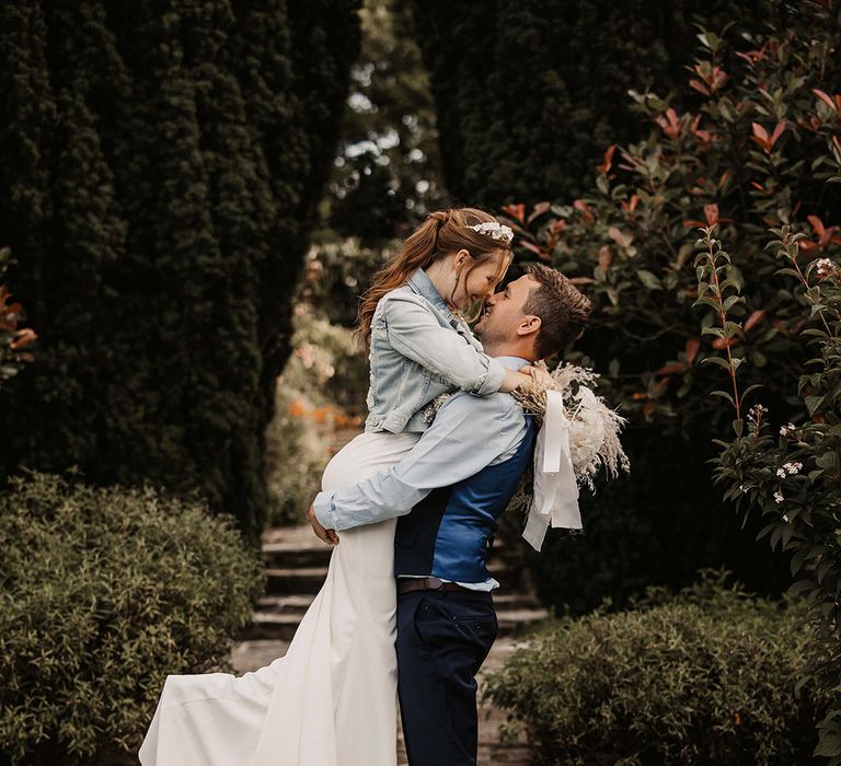 Groom lifts his bride outdoors on their wedding day