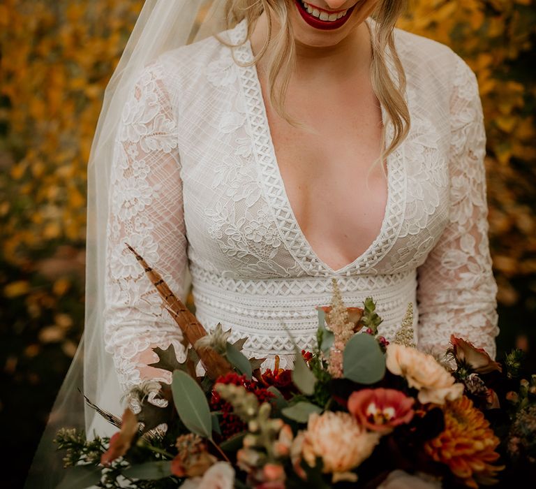 Beautiful bride in a Juliet cap veil with blush cheeks and red lipstick holding her autumnal bouquet 