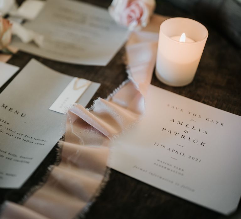 Neutral wedding stationery next to ribbon