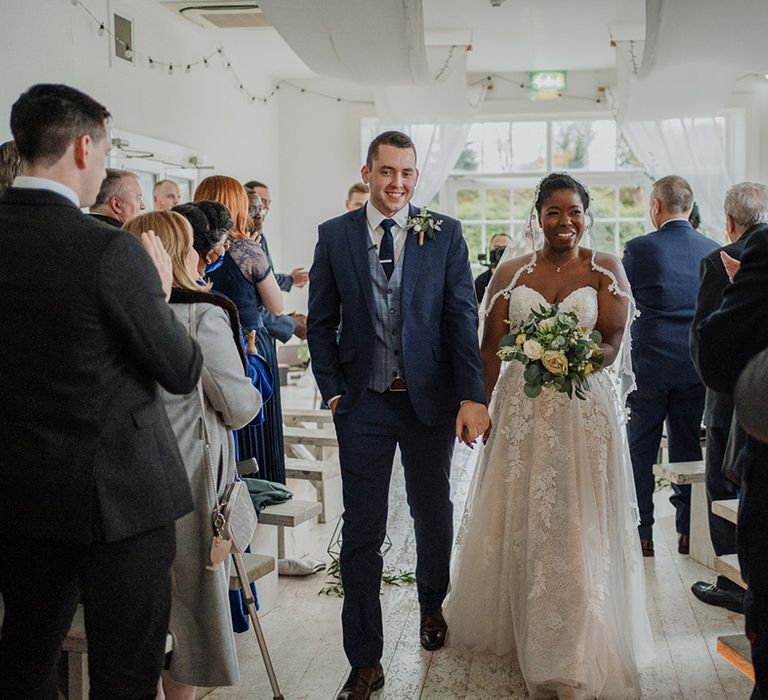 Stunning newly wedded couple walk down the aisle of their classic rustic wedding ceremony 