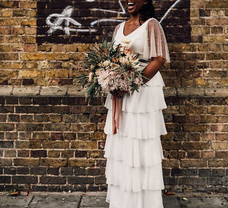 Beautiful Black bride in a layered skirt and pearl top by Story Of My Dress holding a dried and fresh flower wedding bouquet 