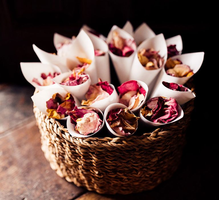 Small round wooden basket full of confetti cones containing white, red and pink dried petal confetti