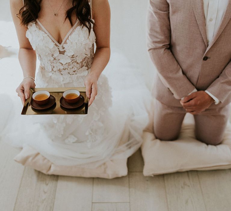 Asian bride and groom kneeling during their Chinese tea ceremony 