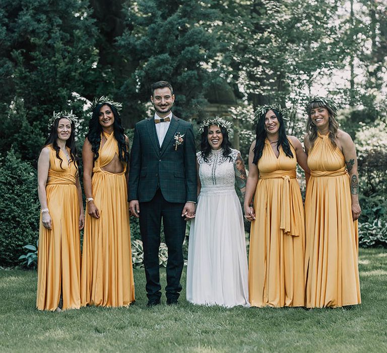 bride & groom stand with bridesmaids who wear yellow bridesmaids dresses in different styles 