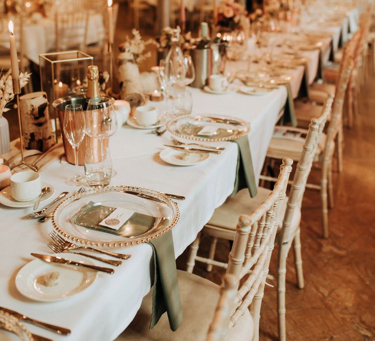 Long white wedding top table with clear plates, green napkins and pink dinner candles for wedding reception at Holmes Mill wedding venue