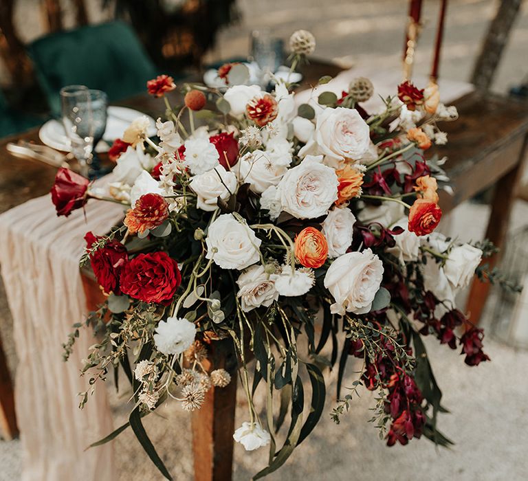 Large red, white and orange wedding flower display with green foliage