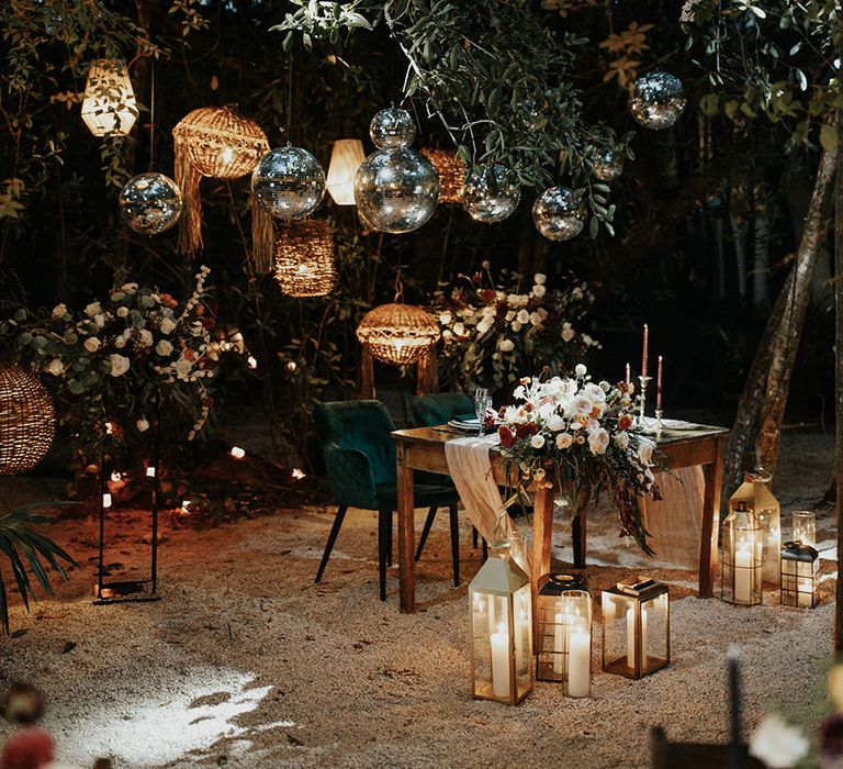 Fun outdoor destination wedding tablescape with green and pink theme with disco balls overhead