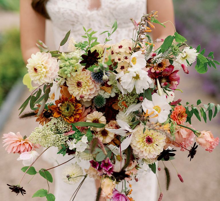 Large wildflower wedding bouquet with pink, red, white, orange and peach flowers with greenery