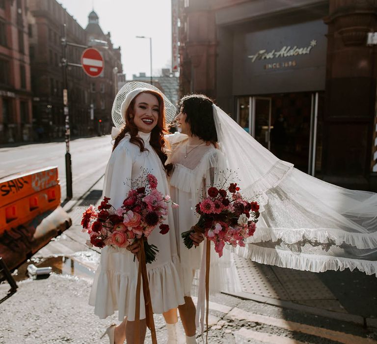 Two brides in Moonchild short wedding dress with long veil and berret at Manchester elopement 