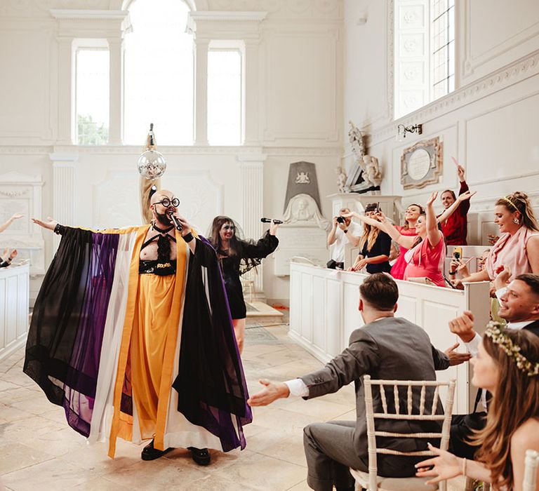 Drag entertainment for wedding with 'Fat Butcher' wearing purple and yellow outfit and cross earrings