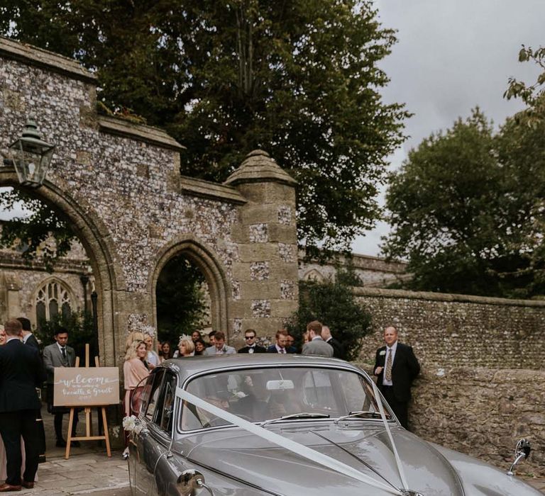 Vintage silver wedding car with white bow and ribbons