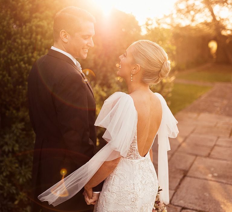 Bride and groom smile at each other for their couple portraits during golden hour