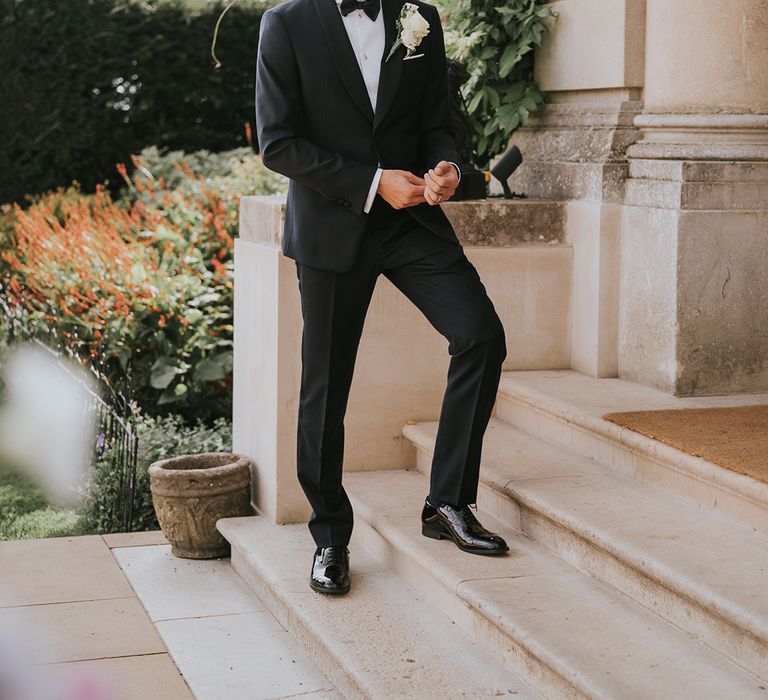 Groom in black tie with white rose buttonhole 