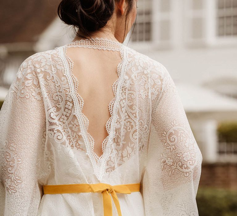 East Asian bride in a lace kimono-style wedding dress red with yellow ribbon with chic bridal up do decorated with fresh flowers 