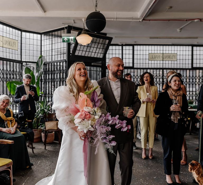 Drinks reception at Floral Hall with bride in a puff sleeve wedding dress holding a pastel wedding bouquet with orchids 