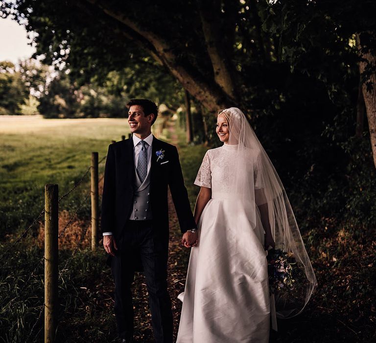 Bride in lace Jesus Peiro wedding dress with groom in a blue and grey morning suit smile