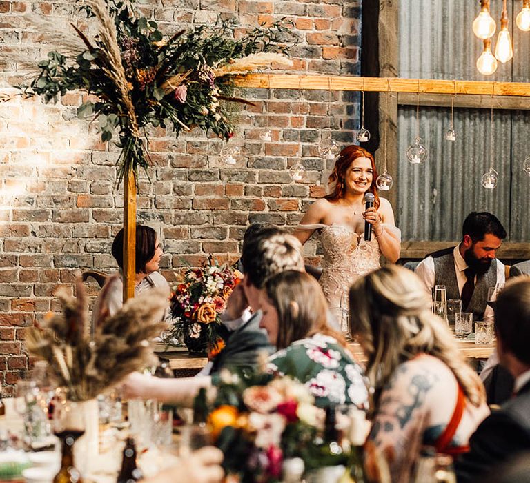 Bride stands up for a bridal speech at their wedding reception 