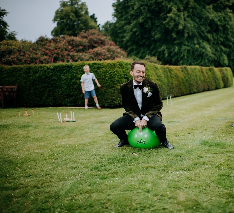 Grooms play garden games outdoors at Birdsall House on their wedding day