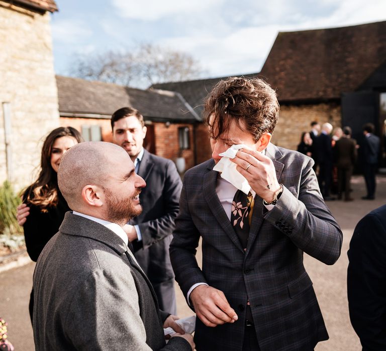 Groom wearing tartan suit and floral tie becomes emotional after wedding ceremony