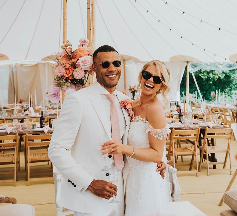 Bride and groom wearing sunglasses for their marquee wedding with dried flowers and pink decor 