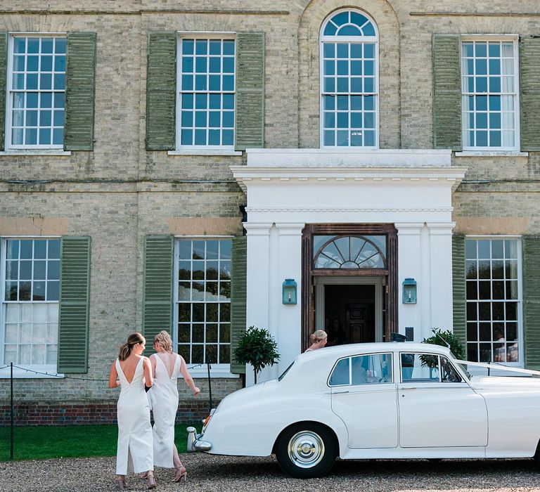 Bridesmaids wear white bridesmaid dresses and walk to Findon Place as white vintage car is parked outside 