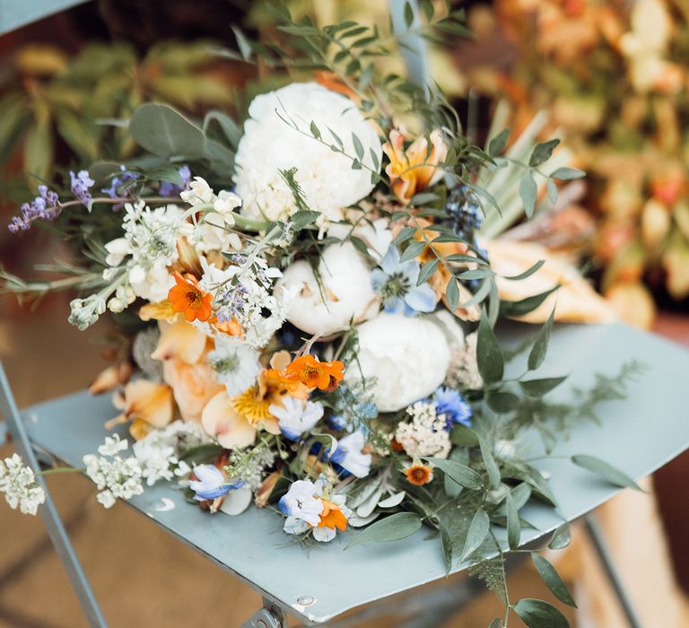 White, orange, blue and purple wedding bouquet with wildflowers 