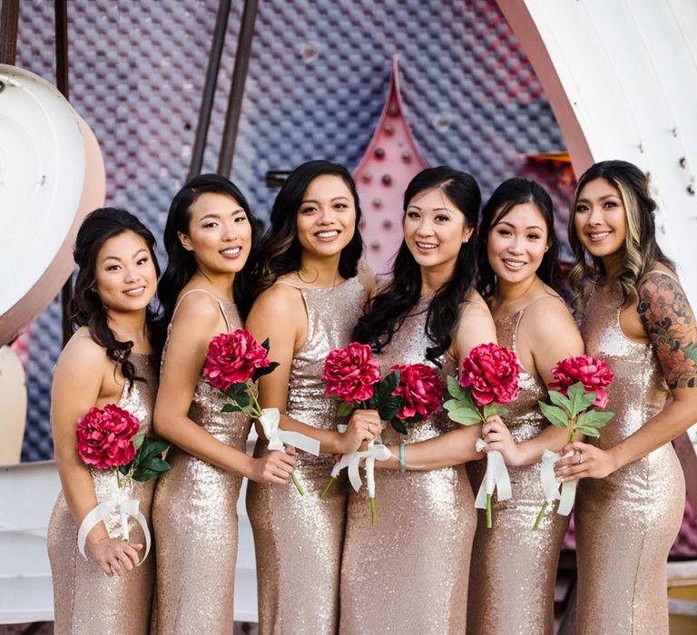 Bridesmaids in gold sequin dresses and a bright pink flower 