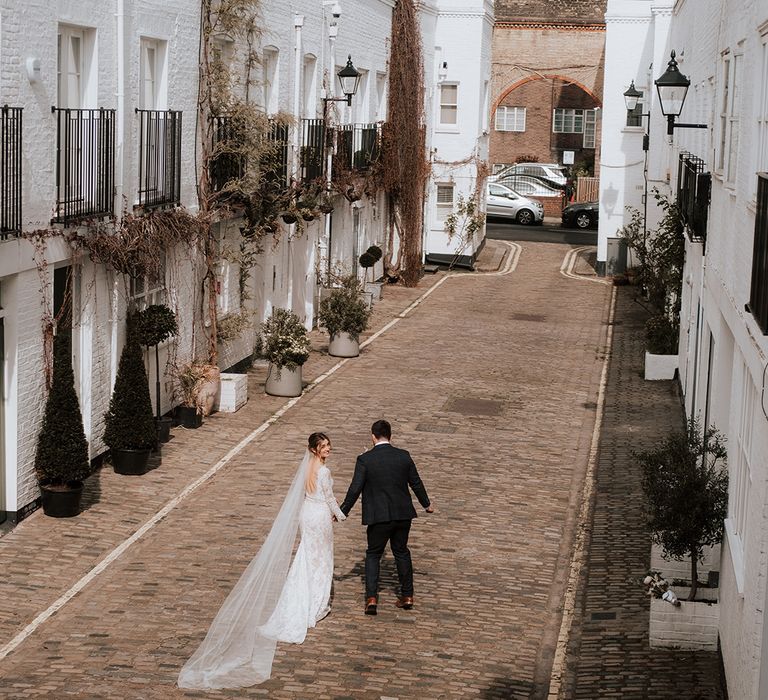 Bride & groom walk down road in Hackney on their wedding day with DIY aspects 