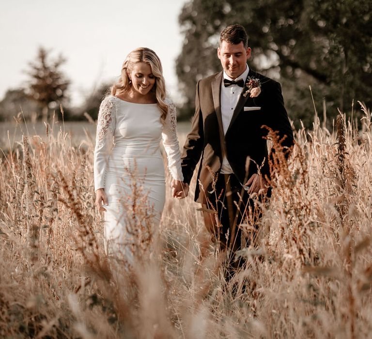 Bride and groom walk holding hands together for classic wedding at Pennard House