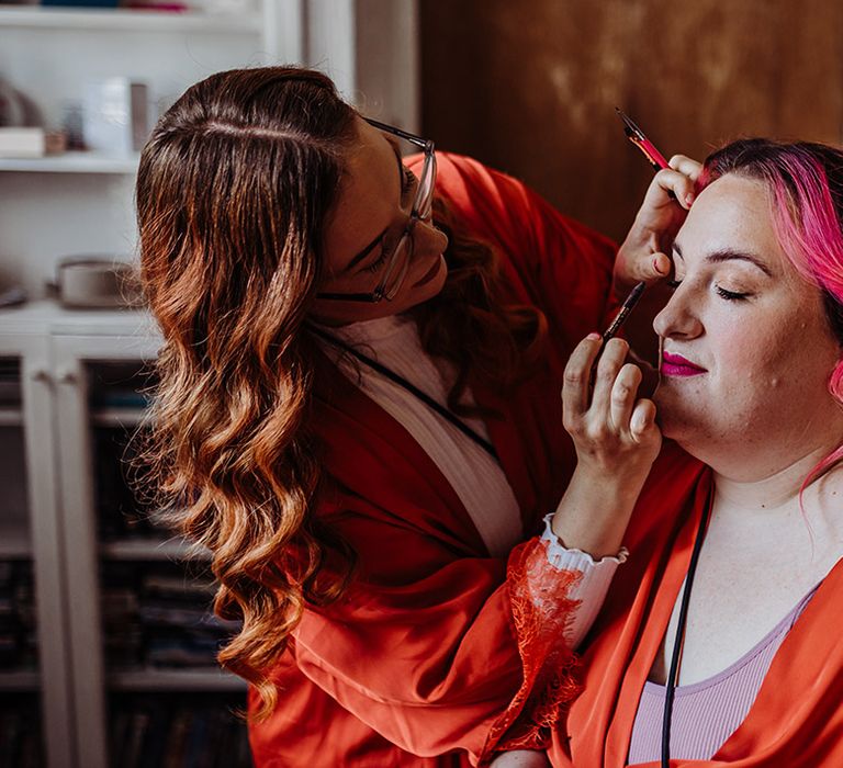 Bride in orange wrap around robe getting makeup done before wedding at Zion venue, Bristol