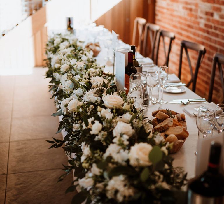 All white wedding flower decoration lining the top table for the bride and groom a rustic wedding with green and white colour scheme 